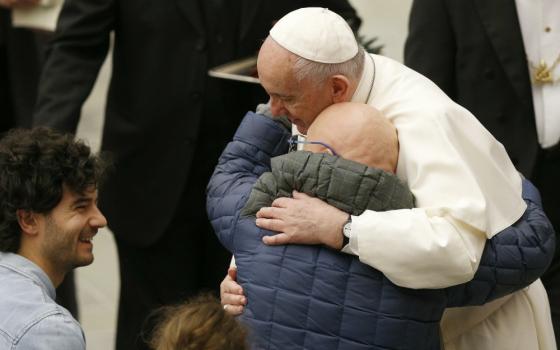 Pope Francis embraces a man as he meets disabled people during his general audience in Paul VI hall at the Vatican Jan. 8. (CNS/Paul Haring)