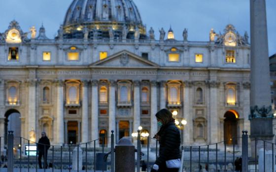 A woman wearing a mask for protection from the coronavirus walks outside St. Peter's Square at the Vatican March 9. (CNS/Paul Haring)