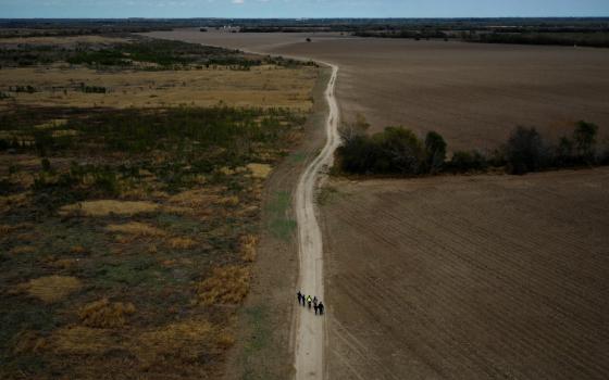 A group of migrants walk past plowed farmland near Penitas, Texas, Jan. 10, 2019. (CNS/Reuters/Adrees Latif)