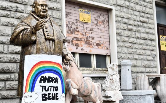 A sign reading "All will be well" hangs on a statue of St. Pope John XXIII in Zogno, Italy, near Bergamo, March 22, 2020. (CNS/Reuters/Flavio Lo Scalzo)