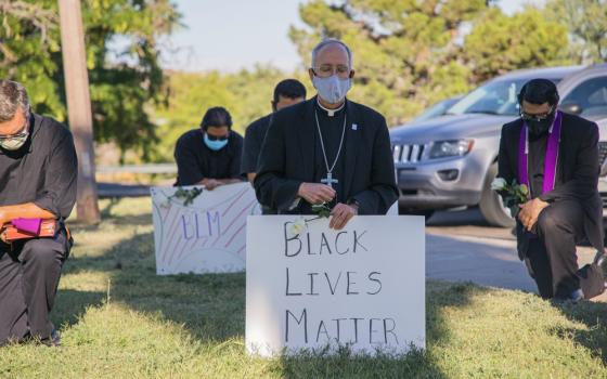 Bishop Mark Seitz of El Paso, Texas, kneels at El Paso's Memorial Park holding a Black Lives Matter sign June 1. (CNS/Courtesy of El Paso Diocese/Fernie Ceniceros)