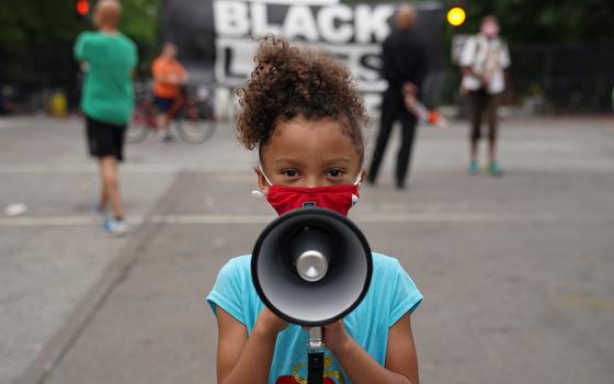 Mischa, 6, from Maryland, holds a bullhorn in front of a "Black Lives Matter" protest sign near the White House June 10, 2020, in Washington. (CNS/Kevin Lamarque, Reuters)