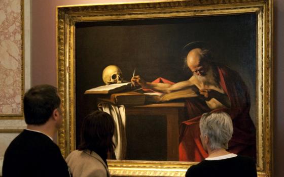 Visitors are pictured in a file photo looking at a Caravaggio painting titled "St. Jerome Writing" during an exhibition at the Galleria Borghese in Rome. Pope Francis released an apostolic letter on the Bible Sept. 30. (CNS/Reuters/Max Rossi)