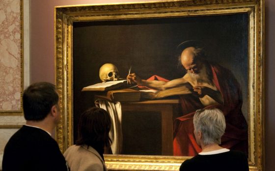 Visitors are pictured in a file photo looking at a Caravaggio painting titled "St. Jerome Writing" during an exhibition at the Galleria Borghese in Rome. Pope Francis released an apostolic letter on the Bible Sept. 30. (CNS/Reuters/Max Rossi)