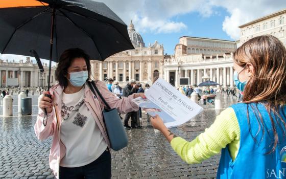 Free copies of the Vatican newspaper L'Osservatore Romano with the front page about Pope Francis' encyclical "Fratelli Tutti" are distributed by volunteers at the end of the Angelus in St. Peter's Square at the Vatican Oct. 4. (CNS/IPA/Reuters/Sipa USA)