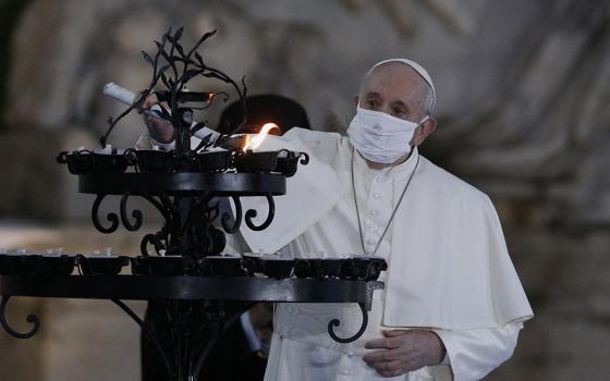 Pope Francis lights a candelabra at the conclusion of an encounter to pray for peace in Piazza del Campidoglio in Rome Oct. 20. (CNS/Paul Haring)