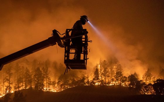 The Glass Fire burns in Calistoga, California, Sept. 28, as an employee of CableCom installs fiber optic cable. (CNS/Adrees Latif, Reuters)