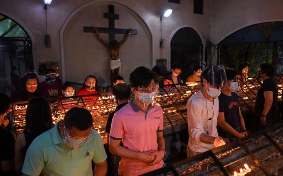 People wearing protective masks and face shields light candles after the first of the nine-day novena Masses for Simbang Gabi at the National Shrine of Our Mother of Perpetual Help in Manila, Philippines, Dec. 16, 2020. (CNS/Reuters/Lisa Marie David)