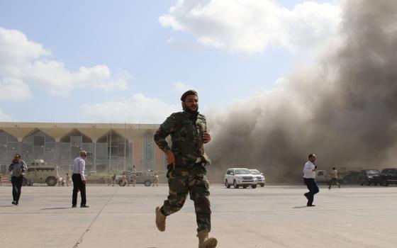 A security member runs during an attack on the airport in Aden, Yemen, Dec. 30, 2020, moments after a plane landed carrying a newly formed Cabinet for government-held parts of the country. (CNS/Fawaz Salman, Reuters)