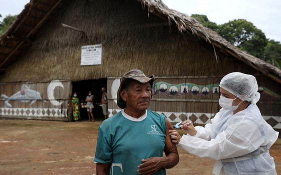 An Indigenous man receives the AstraZeneca/Oxford COVID-19 vaccine from a municipal health worker in the Sustainable Development Reserve of Tupe in Manaus, Brazil, Feb. 9. (CNS/Reuters/Bruno Kelly)