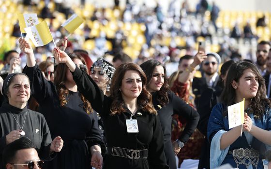 Women wave Vatican flags as they wait for Pope Francis to celebrate Mass at Franso Hariri Stadium in Irbil, Iraq, March 7. (CNS/Paul Haring)