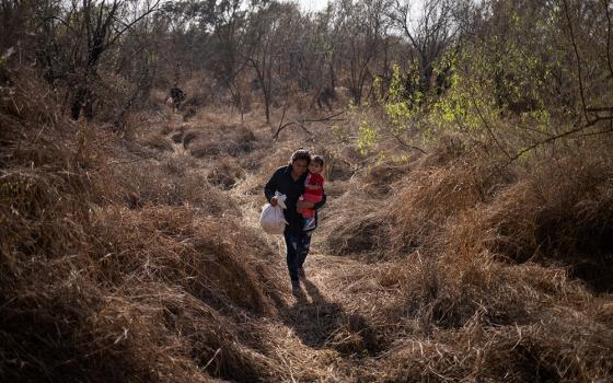 A Honduran migrant carries her baby into Penitas, Texas, after crossing the Rio Grande River from Mexico March 10. (CNS/Adrees Latif, Reuters)