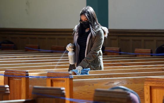 A young woman helps sanitize pews following a memorial Mass in English and Spanish on March 13 for parishioners who have died from COVID-19 at St. John-Visitation Church in the Bronx borough of New York. (CNS/Gregory A. Shemitz)