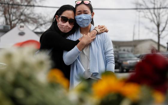 Women in Atlanta embrace March 19, after laying flowers at a makeshift memorial outside the Gold Spa following the deadly shootings March 16 at three day spas in metro Atlanta. Commentator Clarissa V. Aljentera received texts from friends and family, rela