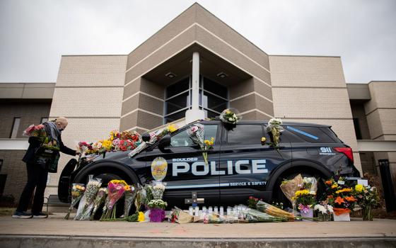 Veronica Hebert of Boulder, Colorado, places flowers on the car of Officer Eric Talley March 23. (CNS/Reuters/Alyson McClaran)