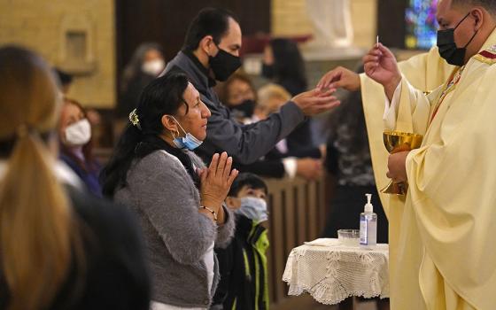 A woman receives Communion during a memorial Mass for Fr. Jorge Ortiz-Garay at St. Brigid Church in Brooklyn, New York, March 27, on the first anniversary of the priest's death from COVID-19.