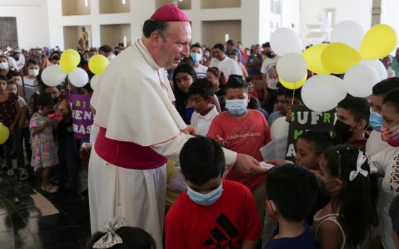 Archbishop Franco Coppola, the apostolic nuncio to Mexico, gives a rosary to a child during a visit to Aguililla April 23. Drug cartels have battled each other and blocked highways in the besieged town, leaving residents unable to travel freely and causin