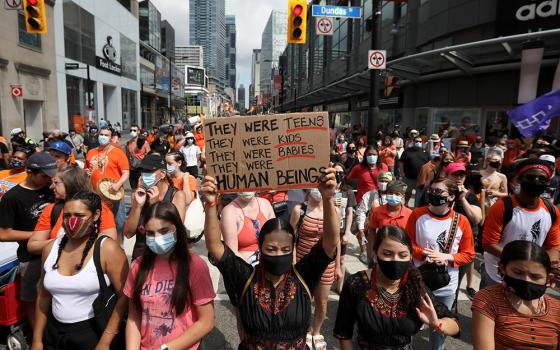 People take part in a march on Canada Day in Toronto July 1, after the discovery of hundreds of unmarked graves on the grounds of former residential schools for Indigenous children in Canada. (CNS/Reuters/Carlos Osorio)