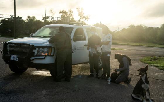 Migrants from Central America are processed July 8 by a Border Patrol agent in Penitas, Texas, after crossing the Rio Grande. (CNS photo/Go Nakamura, Reuters) 