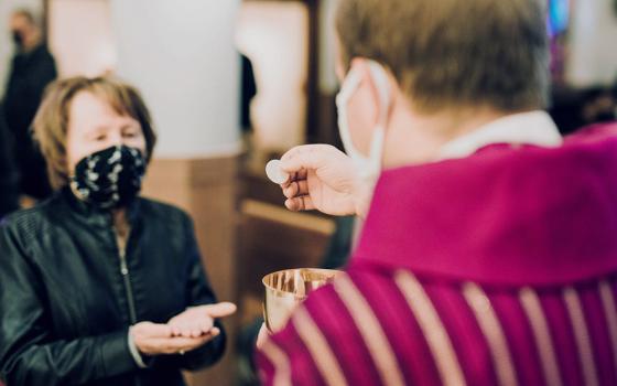 A woman receives Communion at St. John the Baptist Church in Monroe, Michigan, amid the coronavirus pandemic. (CNS/Courtesy of Detroit Catholic)