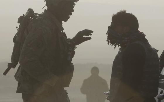 U.S. soldier Sgt. Michael Webb, left, from 549th MP Company Task Force Bronco and a translator are silhouetted as they talk to each other at a joint U.S. military and Afghan police checkpoint in Nangarhar province in eastern Afghanistan March 7, 2012. (CN