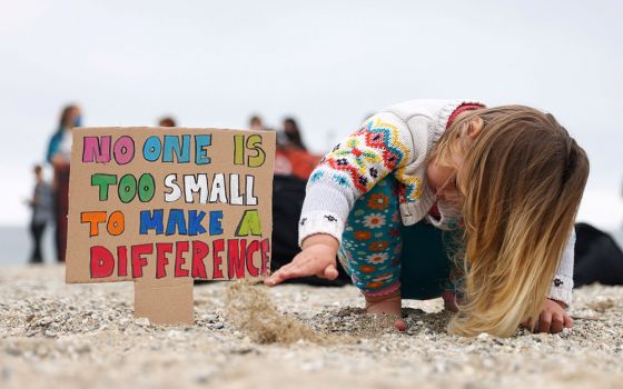 A girl in Falmouth, Britain, plays with sand during a climate protest June 11. (CNS/Reuters/Tom Nicholson)