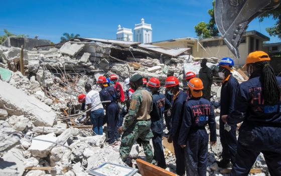 Members of a rescue and protection team clean debris from a house Aug. 15 in Les Cayes, Haiti, following a magnitude 7.2 earthquake the previous day. (CNS/Reuters/Ralph Tedy Erol)