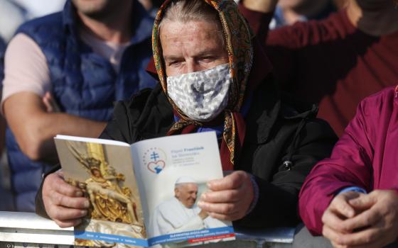 A woman holds the Mass program as she waits for Pope Francis' arrival to celebrate Mass on the plains of the Basilica of Our Lady of Seven Sorrows in Šaštin, Slovakia, Sept. 15, 2021. (CNS photo/Paul Haring)