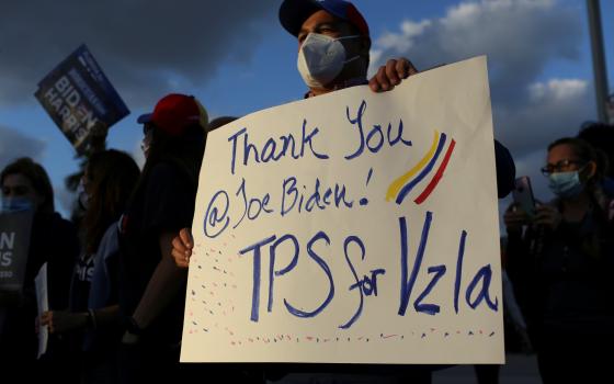 A man in Doral, Fla., holds a sign March 9, 2021, as members of the Venezuelan community react after the Biden administration said it would grant Temporary Protected Status to Venezuelan immigrants living in the United States. (CNS photo/Marco Bello, Reut