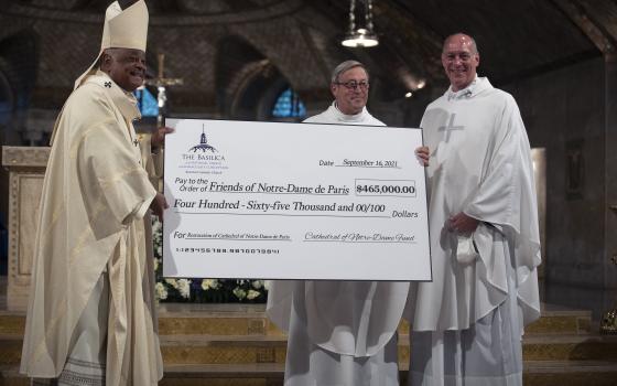 Msgr. Patrick Chauvet, center, rector of the Notre Dame Cathedral in Paris, receives a check from Msgr. Walter Rossi, rector of the Basilica of the National Shrine of the Immaculate Conception in Washington, and Washington Cardinal Wilton D. Gregory after