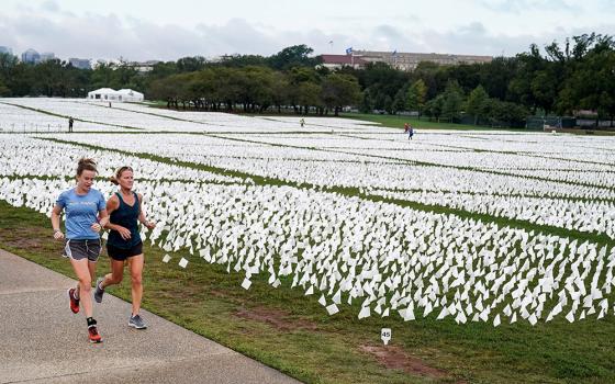 Women in Washington run past an exhibition of white flags at the National Mall Sept. 17, that represent Americans who have died of the coronavirus disease. (CNS/Reuters/Joshua Roberts)