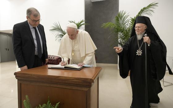 Pope Francis signs documents alongside Vincenzo Buonomo, rector of Rome's Pontifical Lateran University, and Ecumenical Patriarch Bartholomew of Constantinople, at the university Oct. 7, 2021. The event was to launch a new chair supported by UNESCO "On Fu