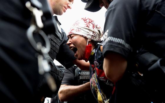 A demonstrator near the White House in Washington is arrested by U.S. Secret Service agents Oct. 11, during a climate change protest to mark Indigenous Peoples Day. (CNS/Reuters/Evelyn Hockstein)