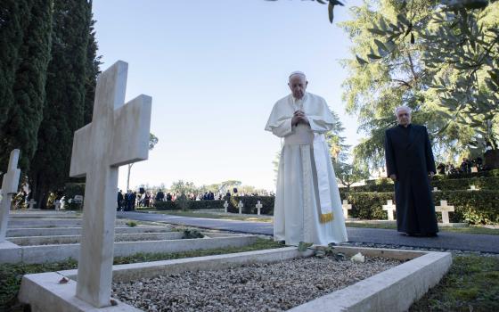 Pope Francis prays at a grave at the French Military Cemetery before celebrating Mass for the feast of All Souls at the cemetery in Rome Nov. 2, 2021. (CNS photo/Vatican Media)