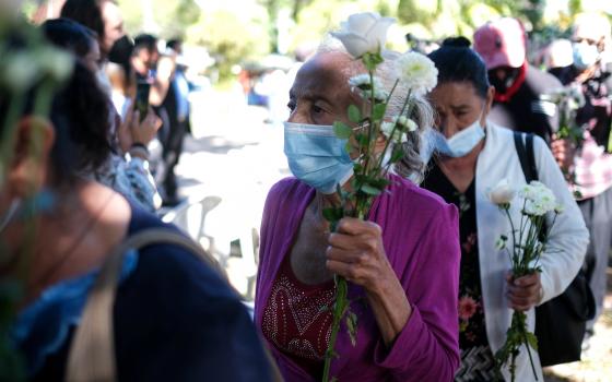 Women carry flowers as the arrive to take part in a ceremony to commemorate the 40th anniversary of the El Mozote massacre in El Salvador Dec. 11, 2021. (CNS photo/Jose Cabezas, Reuters)