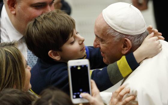 A boy embraces Pope Francis during his general audience in the Paul VI hall at the Vatican Dec. 15, 2021. (CNS photo/Paul Haring)