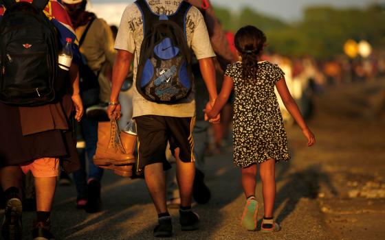 Jose Francisco from Honduras leads his 8-year-old daughter, Zuabelin, by the hand Nov. 22, 2021, as they took part in a caravan near Villa Mapastepec, Mexico, and headed to the U.S. border. (CNS photo/Jose Luis Gonzalez, Reuters)