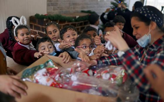 A teacher hands out to students Christmas-themed gifts at Rosary Sisters' School in Gaza City Nov. 24, 2021. (CNS photo/Mohammed Salem, Reuters)