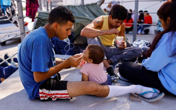 Venezuelan migrants, expelled from the U.S., eat at the U.S.-Mexico border in Ciudad Juarez, Mexico, Oct. 16, 2022. They were sent back to Mexico under Title 42 as part of a new policy to curb the number of illegal crossings. (CNS photo/Jose Luis Gonzalez, Reuters)