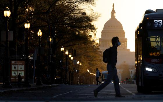 A pedestrian crosses Pennsylvania Avenue as the sun rises over the U.S. Capitol in Washington Nov. 9. (CNS/Reuters/Tom Brenner)