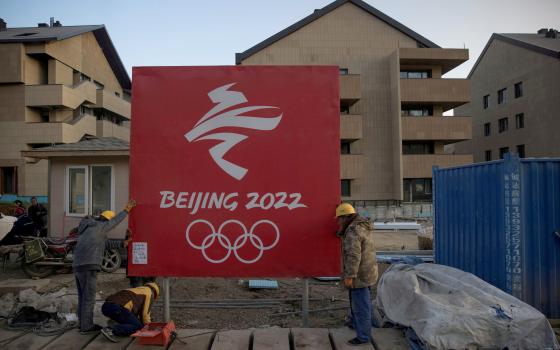 Workers move a sign Oct. 29, 2020, at the Thaiwoo ski resort near skiing venues of the 2022 Winter Olympics in Chongli, a popular ski resort town in China. (CNS photo/Thomas Peter, Reuters)