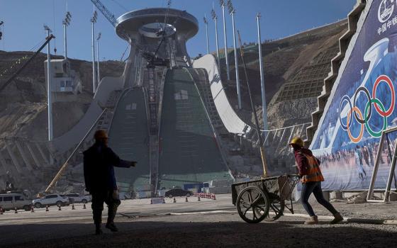 Workers are silhouetted Oct. 29, 2020, at the Thaiwoo ski resort near skiing venues of the 2022 Winter Olympics in Chongli, a popular ski resort town in China. The venue is one of many in the Beijing area that will host the Olympic Winter Games Feb. 4-20.