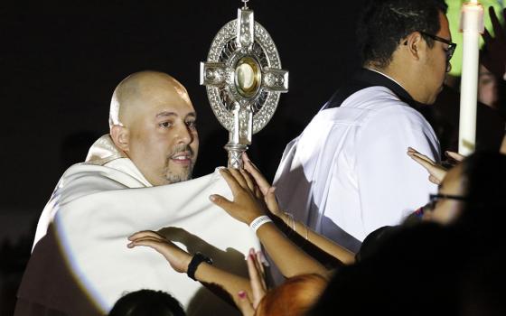 Fr. Joseph Espaillat carries a monstrance through the bleachers of Carnesecca Arena during eucharistic adoration at the Steubenville New York youth conference at St. John's University June 25, 2016, in Jamaica, New York. (CNS/Gregory A. Shemitz)