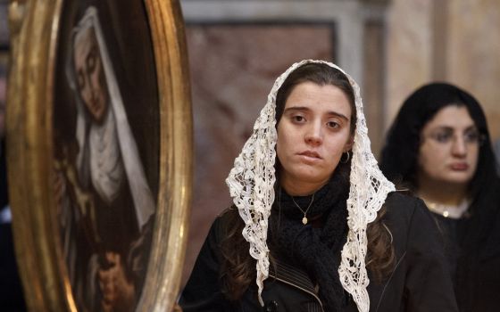 Maria Regina Zucchi of São Paulo stands near a painting of a saint at the Church of the Holy Trinity of the Pilgrims, a Fraternity of St. Peter parish, in Rome, Nov. 1, 2012. (CNS photo/Paul Haring)