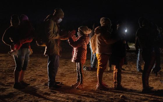 Romando, a migrant from Peru seeking asylum in the United States, plays a hand-clapping game with his daughter Alexa, 7, as they stand in line waiting to be processed in Roma, Texas, Feb. 28, 2022. (CNS photo/Adrees Latif, Reuters)