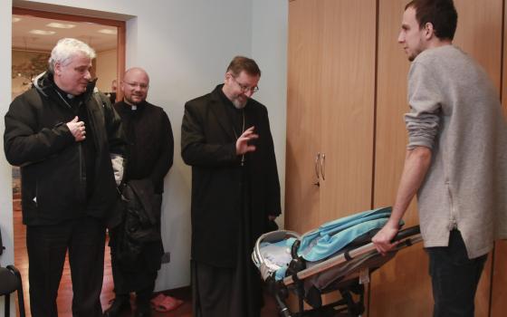 Archbishop Sviatoslav Shevchuk of Kyiv-Halych, head of the Eastern-rite Ukrainian Catholic Church, waves to a child as he and Cardinal Konrad Krajewski, left, the papal almoner, visit with Ukrainian refugees in Lviv, Ukraine, March 10, 2022. (CNS photo/co