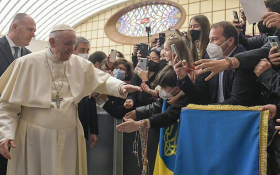 Pope Francis walks near a flag with the national colors of Ukraine during his general audience in the Paul VI hall at the Vatican March 16. (CNS/Vatican Media)