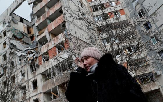 A woman reacts in front of destroyed apartment buildings in Mariupol, Ukraine, March 17, 2022.