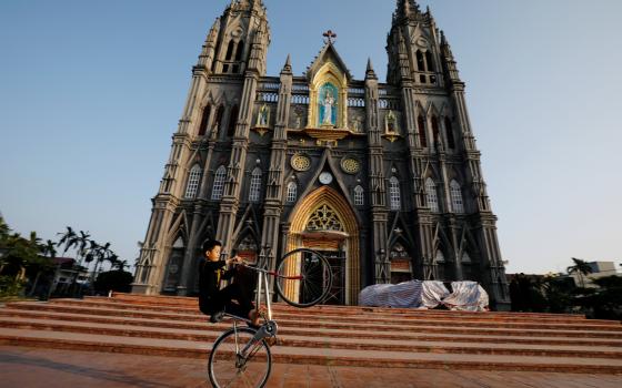 A boy in Nam Dinh, Vietnam, cycles in front of a church Dec. 6, 2020. (CNS photo/Kham, Reuters)