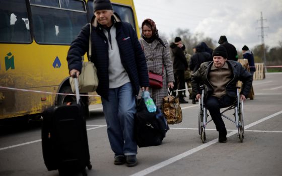 Ukrainian refugees in Zaporizhzhia, Ukraine, walk towards a registration center for internally displaced people April 21, 2022, after arriving in a small convoy that crossed through a territory held by Russian forces. (CNS photo/Ueslei Marcelino, Reuters)